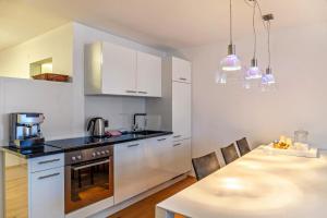 a kitchen with white cabinets and a dining table at Haus Excelsior Top 30 in Seefeld in Tirol