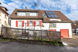 a white house with red doors and a fence at Ferienwohnung am Blitzgi in Wehr
