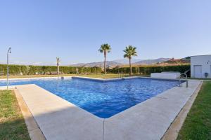 a swimming pool in a yard with palm trees at Apartamento Baviera Golf 002 in Vélez-Málaga