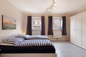 a bedroom with a bed and two windows at Sabines Ferienwohnung 2 in Glückstadt