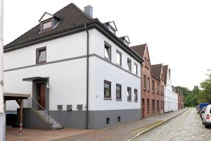 a white house with a black roof on a street at Sabines Ferienwohnung 2 in Glückstadt
