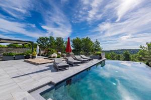 a swimming pool with lounge chairs and a red umbrella at Prestigieuse Villa Spa 2 Piscines in Saint-Gély-du-Fesc