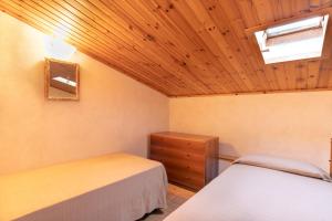 a bedroom with two beds and a wooden ceiling at Simona Giardino in Fetovaia
