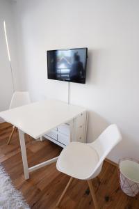a white desk and chair with a tv on a wall at Zentral und Naturnah in Penzberg +3 photos