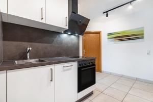 a kitchen with white cabinets and a black stove top oven at Fewo Gartenblick in Oberharmersbach