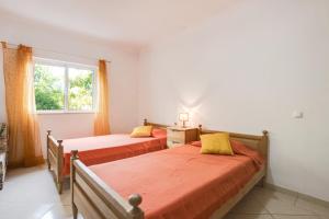 two beds in a bedroom with a window at Casa das Romanzeiras in Carvoeiro +22 photos