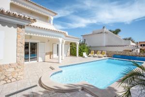 a villa with a swimming pool and a house at Casa das Romanzeiras in Carvoeiro