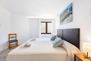 a bedroom with a large bed and a chair at Albercutx Pollentia 3 in Pollença