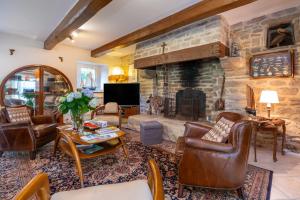 a living room with leather chairs and a stone fireplace at Ty Al Louarn - Piscine - Spa in Brech