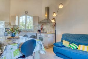 a kitchen and living room with a blue couch at La Madrague St Vincent Apt A in Le Grau-dʼAgde