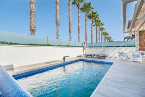 a swimming pool with palm trees in the background at Belle in Orihuela Costa