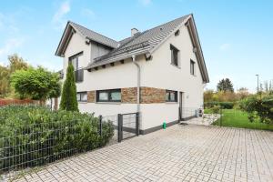 a white house with a black roof and a brick driveway at Ferienwohnung Familie Arnhofer in Waal