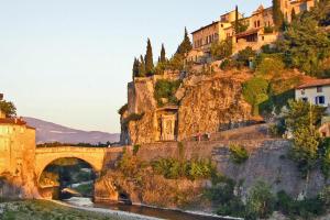 a bridge over a river with houses on a mountain at Le Vieil Olivier in Sahune
