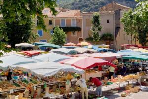 a group of people standing around a market with umbrellas at Le Vieil Olivier in Sahune