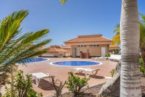 a house with two pools and a palm tree at Chasna Sunset in Adeje
