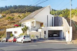 a white building with cars parked in a parking lot at Villa Aurélio in Campanário