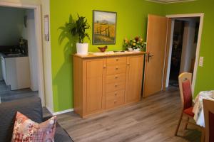 a living room with green walls and a wooden dresser at Fewo-rosenberger-sauerland in Lennestadt