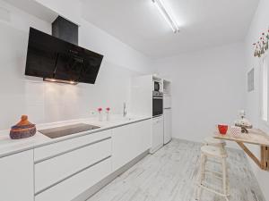 a kitchen with white cabinets and a flat screen tv on the wall at Casa Convent in Alcudia