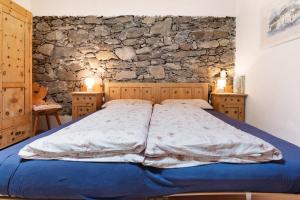 a bed in a bedroom with a stone wall at Bachguthof in Silandro