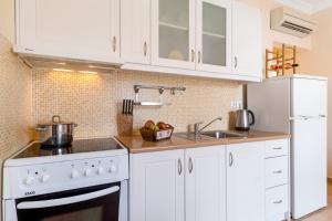 a kitchen with white cabinets and a sink and a refrigerator at Villa Captain Fotis 4 in Póndi