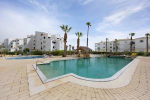a swimming pool in a resort with palm trees and buildings at Sol do Atlântico in Portimão