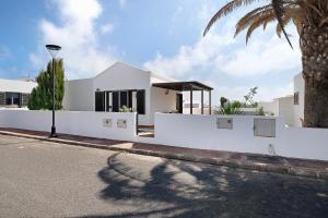 a white house on a street with a palm tree at El Charco Azul in Charco del Palo