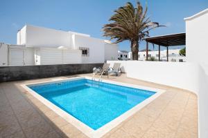a swimming pool in front of a white house at El Charco Azul in Charco del Palo