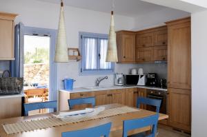 a kitchen with wooden cabinets and a table with blue chairs at Villa St' Astra in Koufonisia