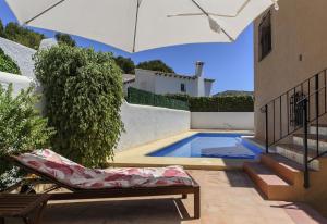 a swimming pool with an umbrella next to a house at Vista Bahía in Moraira