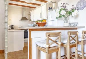 a kitchen with white cabinets and a counter with chairs at Vista Bahía in Moraira