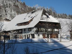 a large building covered in snow with snow covered trees at Rinkenbachhof in Schenkenzell