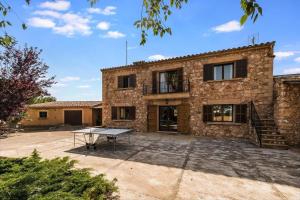 a stone house with a table in front of it at Finca Can Moleta in Cala Mendia