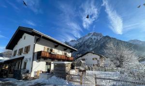 a house in the snow with a mountain in the background at Ferienwohnung Bienennest in Mittenwald