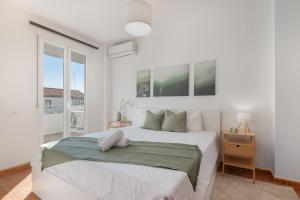 a white bedroom with a large bed and a window at Villa Marília in Ayamonte