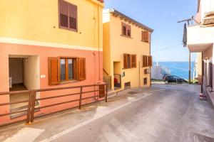 an empty street with two buildings and a car at Centralissimo Charlie Beach in Castelsardo