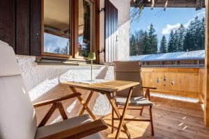a wooden table and chairs on a porch with a window at Fewo Am Steinbach - Stoaboch in Reit im Winkl