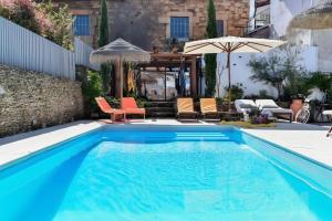 a swimming pool with chairs and an umbrella at Casa Douro Janja in Armamar