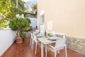 a white table and chairs on a patio with plants at Casa Chloe in Nerja