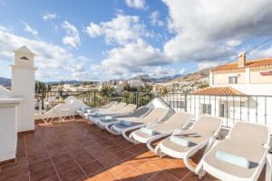 a row of lounge chairs on the roof of a building at Casa Chloe in Nerja