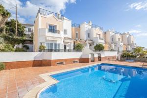 a villa with a swimming pool in front of a building at Casa Chloe in Nerja