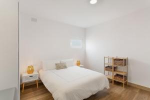 a white bedroom with a white bed and two tables at Bastion del Drago in Arucas