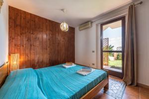 a bedroom with a blue bed and a window at Casa Michelle in Villaputzu