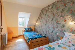 a bedroom with two beds and a wall with floral wallpaper at Le paradis sur mer in Paimpol