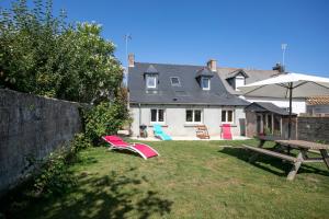a yard with a picnic table and chairs and a house at Le paradis sur mer in Paimpol