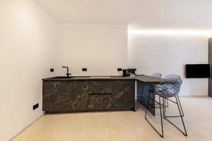 a kitchen with a counter with a sink and two chairs at App 203 Palazzo Cavour in Bolzano