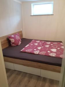 a small bedroom with a bed with a red comforter at Lila Pause in Ellweiler