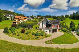 a house on a green hill with a driveway at Ferienwohnung Bergahorn in Todtnauberg