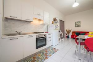 a kitchen with white cabinets and a table with red chairs at Gerani Rossi Appartamento in Villa San Pietro +20 photos