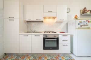 a white kitchen with white cabinets and an oven at Gerani Rossi Appartamento in Villa San Pietro