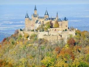 a castle on top of a hill with trees at Ferienwohnungen Im Eugenhaus in Rosenfeld